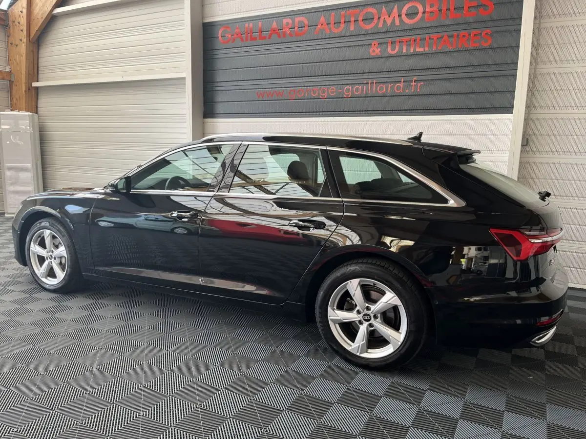 Audi A6 40 TDI S Tronic hybride noire vue de profil côté gauche dans un garage avec sol damier.