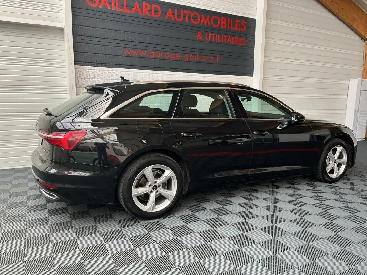 Audi A6 noire vue de profil côté gauche, break élégant avec jantes argentées et feux arrière LED distinctifs.