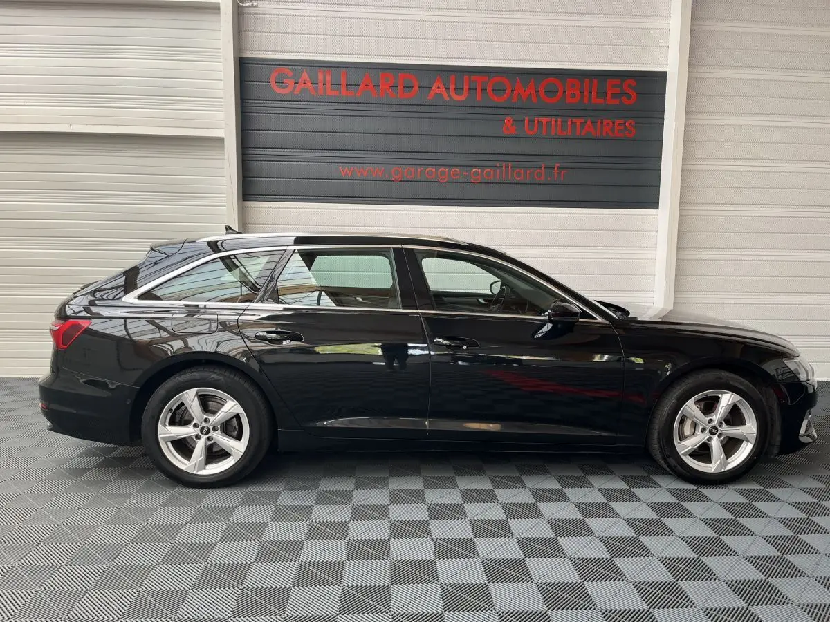 Profil latéral droit d'une Audi A6 noire 40 TDI S Tronic hybrid 2022, stationnée en intérieur sur sol damier.