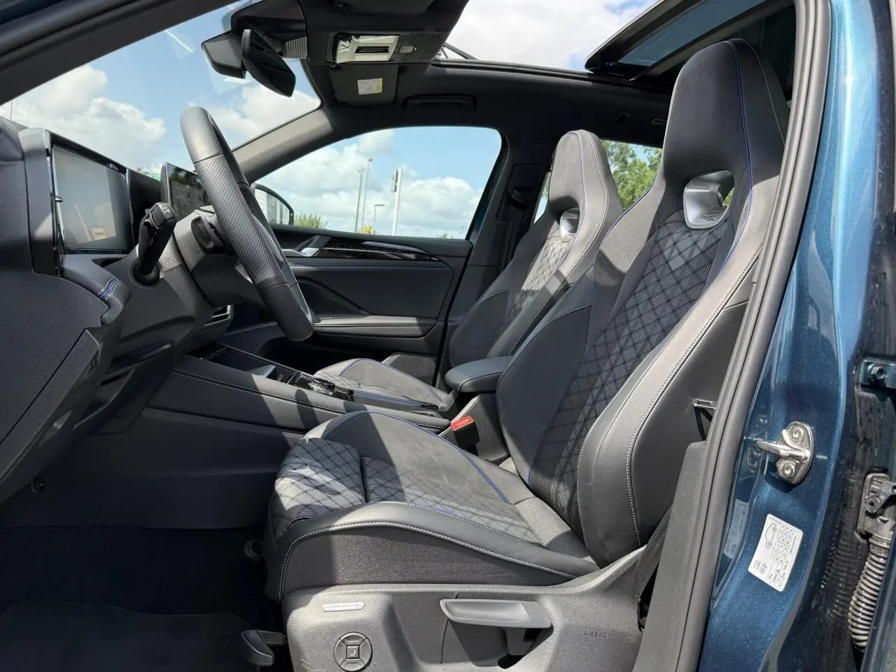 Intérieur côté conducteur du Volkswagen Tiguan 2024 bleu Nightshade, sièges sport R-Line en cuir et alcantara avec surpiqûres bleues.