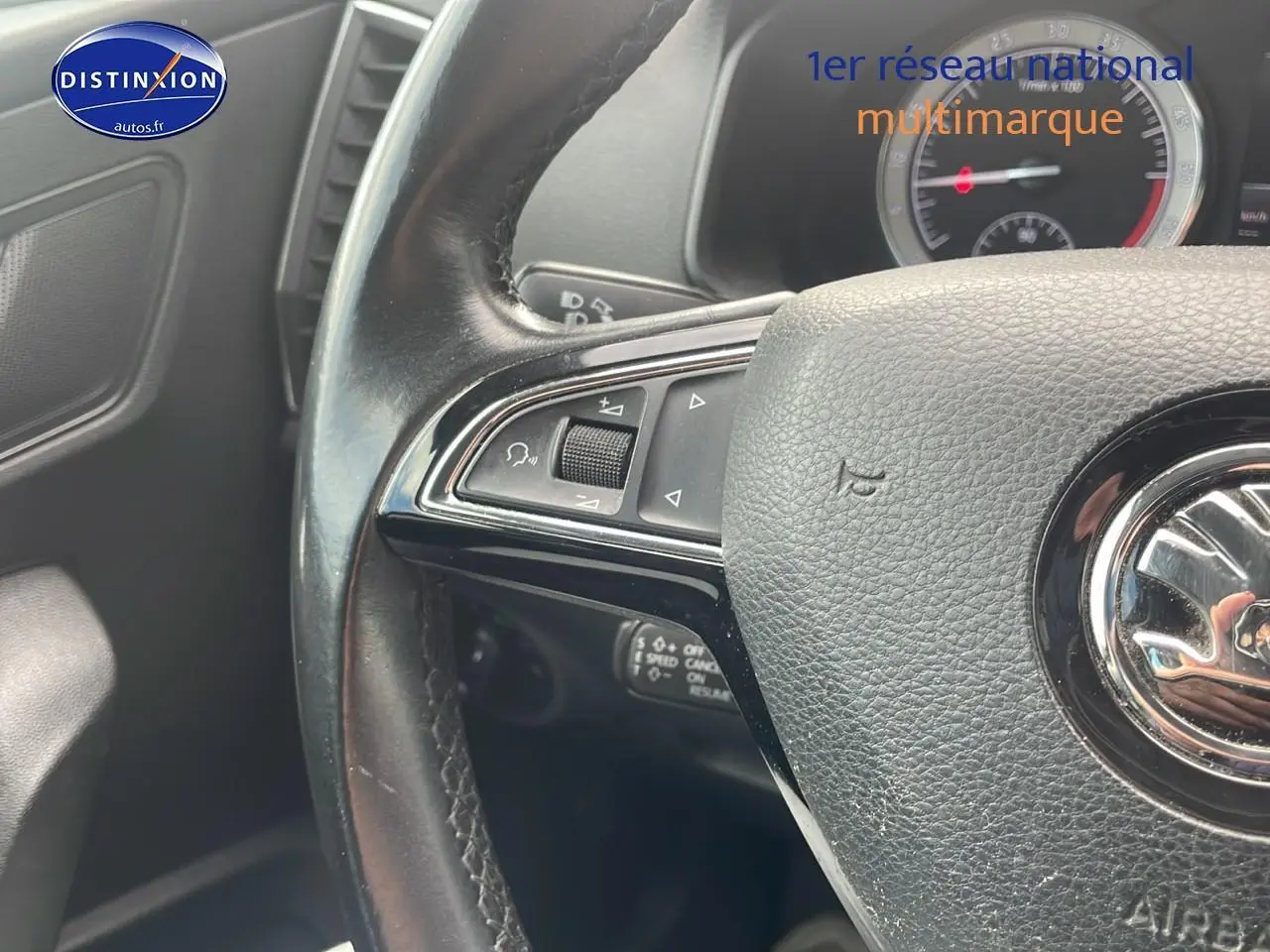 Gros plan sur le volant cuir multifonction noir d'une Skoda Karoq 2018 avec commandes intégrées côté gauche.