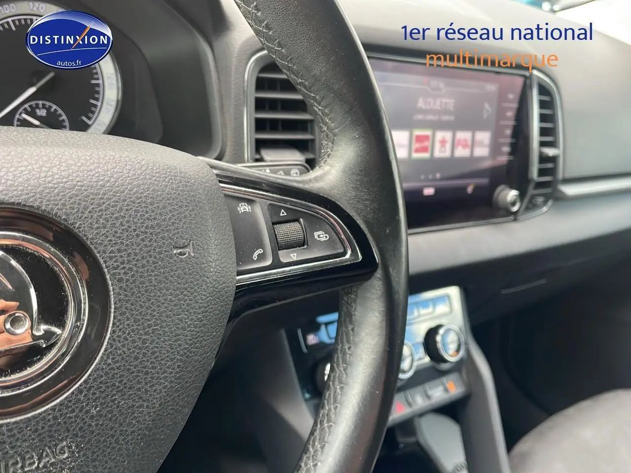 Gros plan sur le volant cuir multifonction et l'écran tactile du tableau de bord intérieur d'une Skoda Karoq noire 2018.