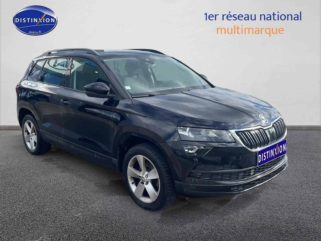 Vue 3/4 avant droite d'un Skoda Karoq noir 2018 avec jantes alu et barres de toit visibles.