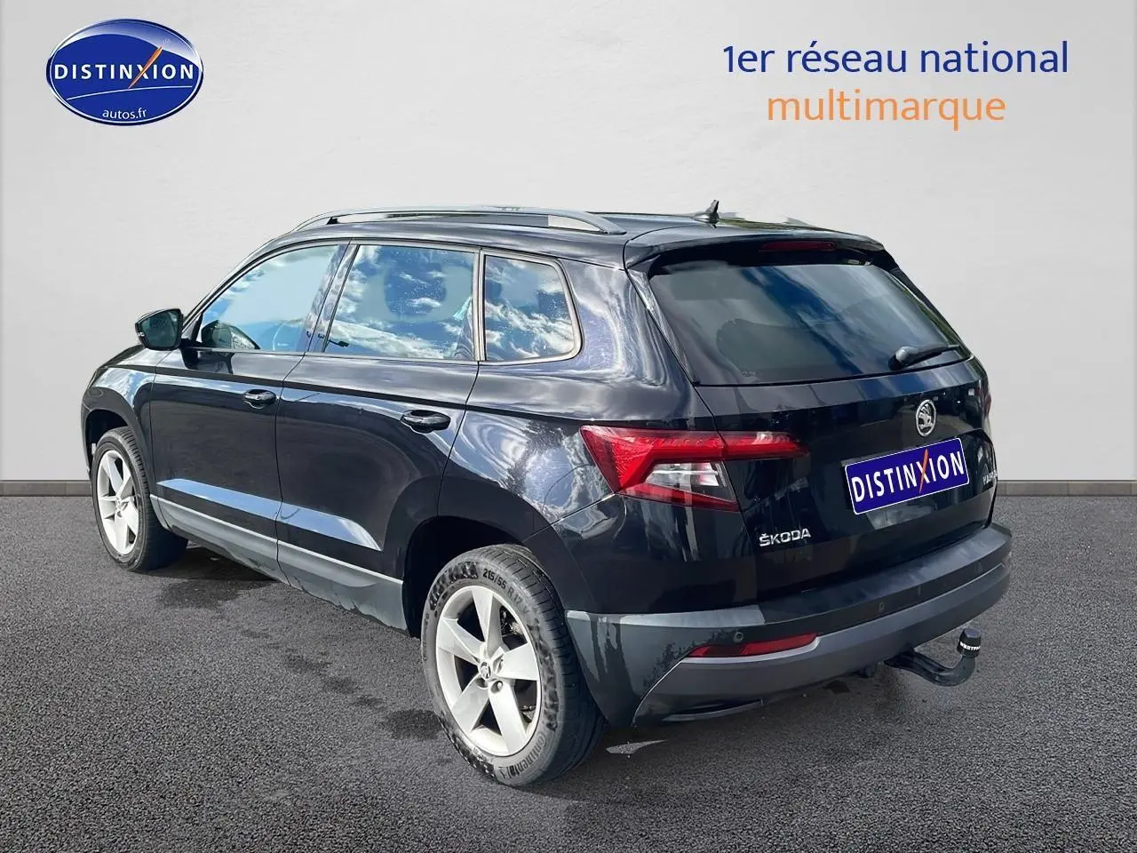 Vue 3/4 arrière droite d'un Skoda Karoq noir avec barres de toit et attelage de remorque visible.