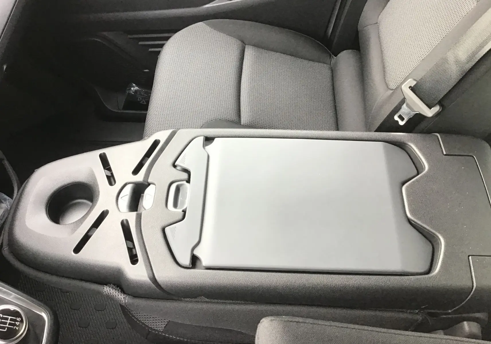 Détail de la console centrale noire avec porte-gobelet et accoudoir du Renault Trafic Fourgon blanc, version 2025.