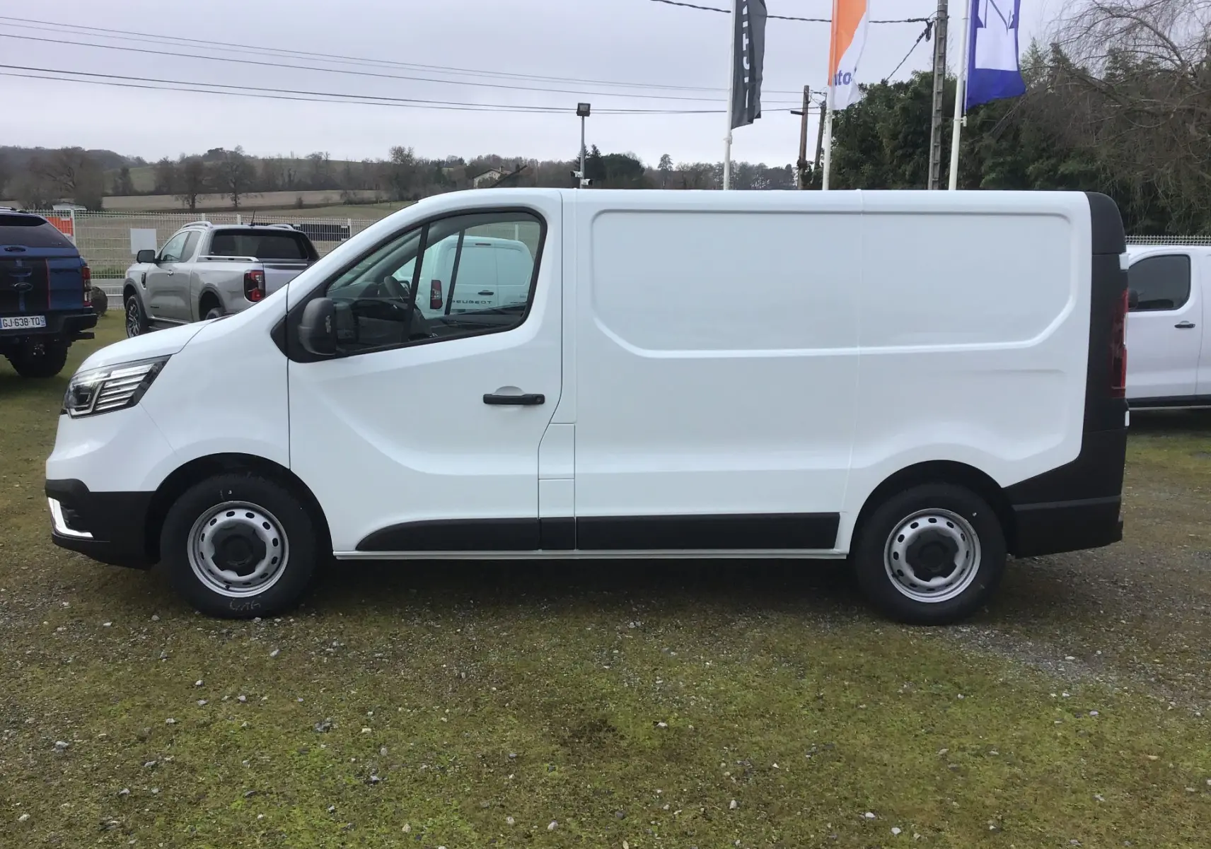 Vue de profil côté gauche d’un Renault Trafic Fourgon blanc 2025 avec porte latérale coulissante et jantes acier.
