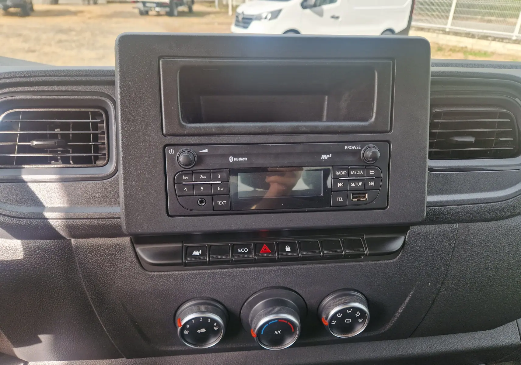 Tableau de bord noir du Renault Master Châssis Cabine 2024, vue frontale centrée sur la radio et les commandes de climatisation.