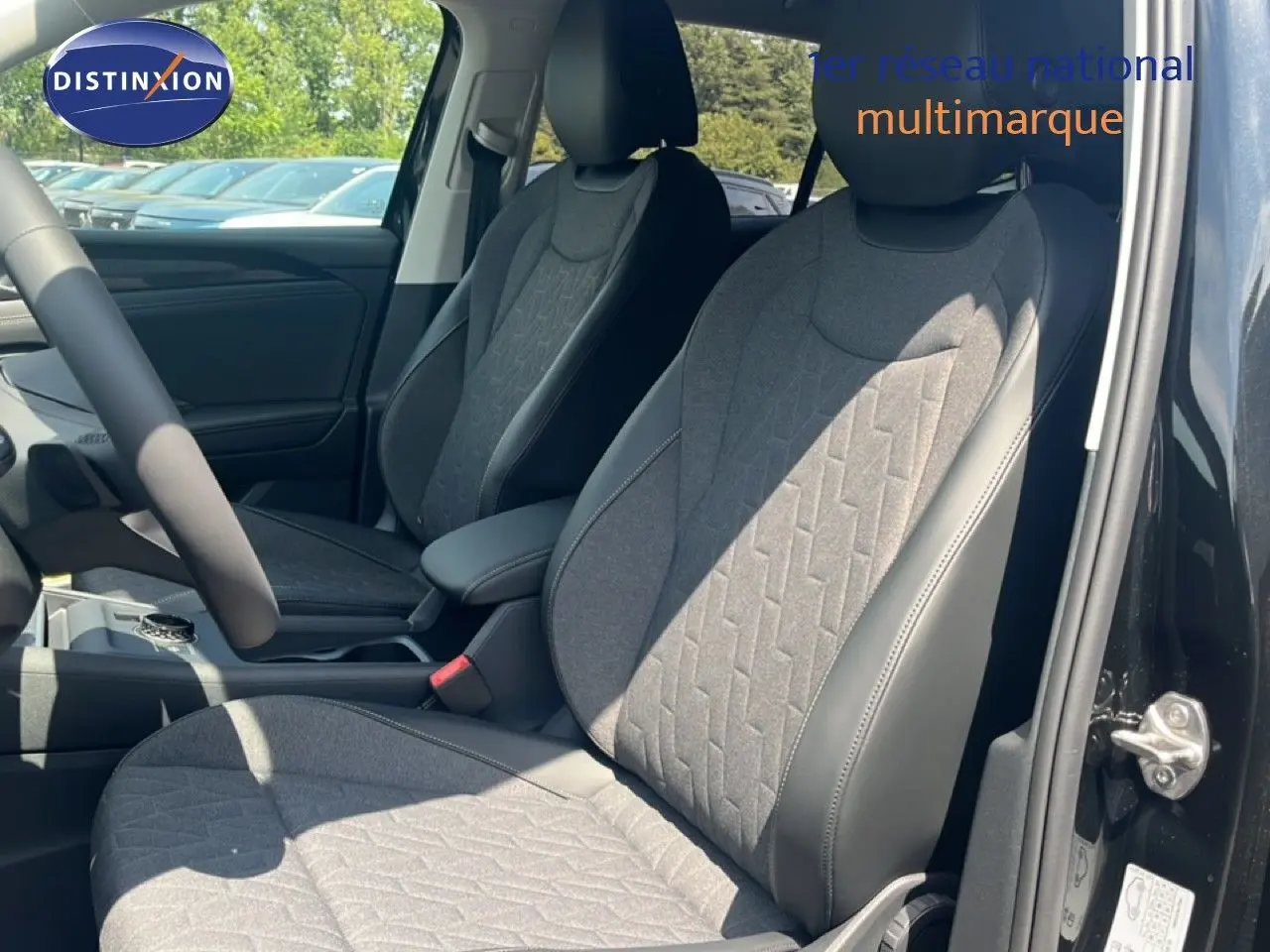 Vue intérieure côté conducteur du Volkswagen Tiguan 2026 noir Grenadilla, sièges tissu et cuir gris avec motifs géométriques.