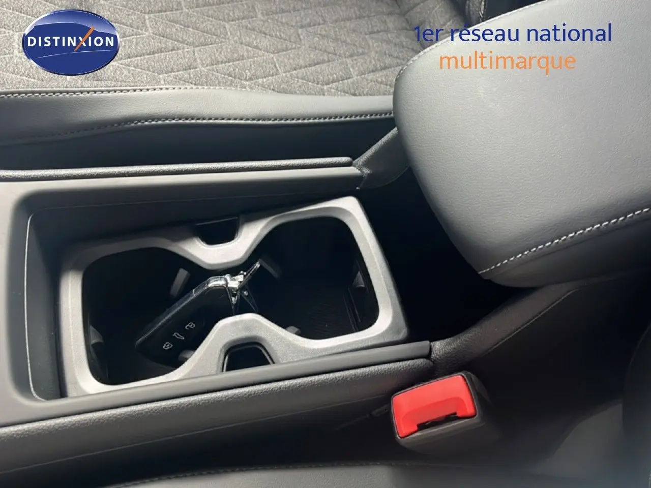 Gros plan intérieur sur la console centrale noire du Volkswagen Tiguan 2026 avec clé dans porte-gobelets et accoudoir cuir.