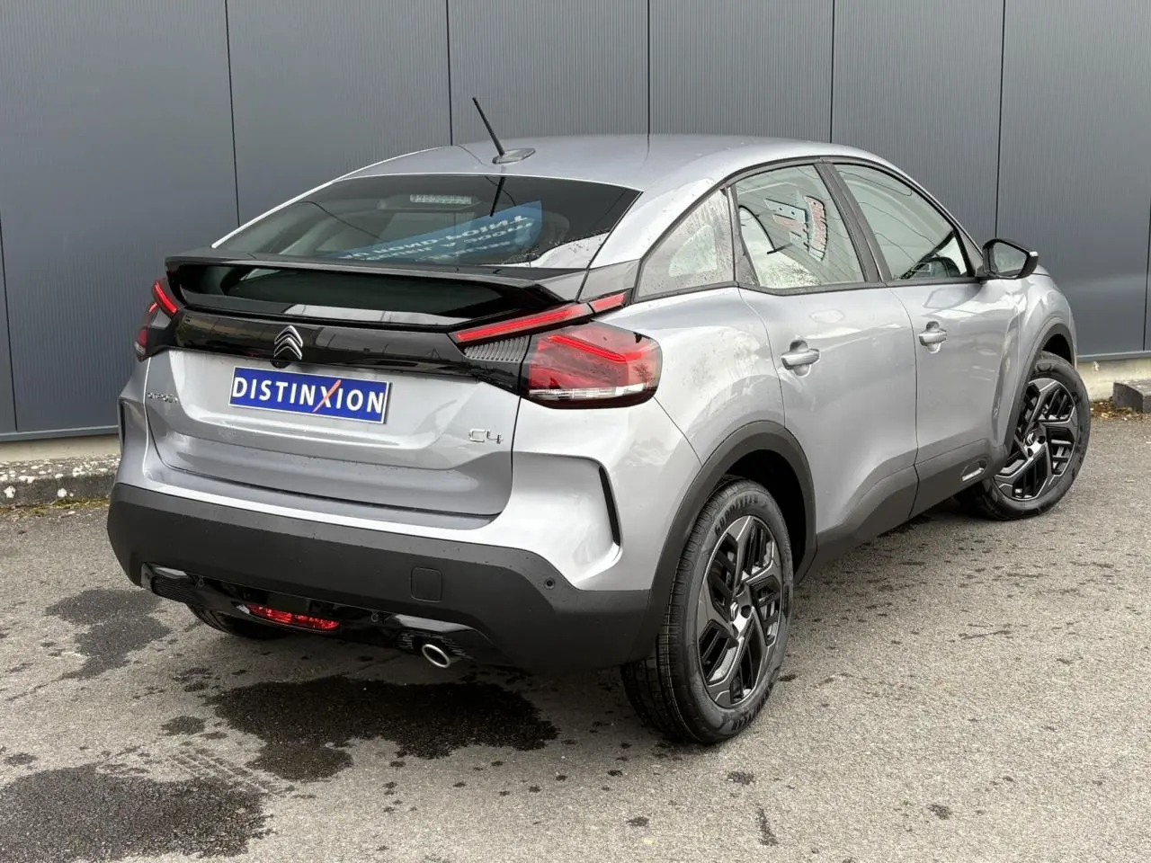 Vue 3/4 arrière droite d'une Citroën C4 gris acier avec jantes alliage noires et feux arrière LED distinctifs.