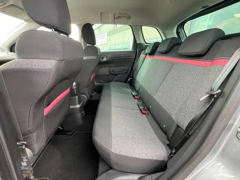 Vue intérieure arrière côté droit du Citroën C3 Aircross gris acier avec banquette tissu C-Series et bande rouge décorative.