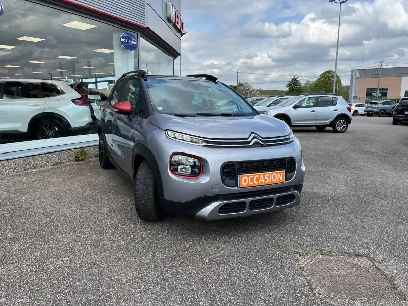 Citroën C3 Aircross gris acier vue 3/4 avant avec coques de rétroviseurs rouges et plaque "OCCASION" visible.