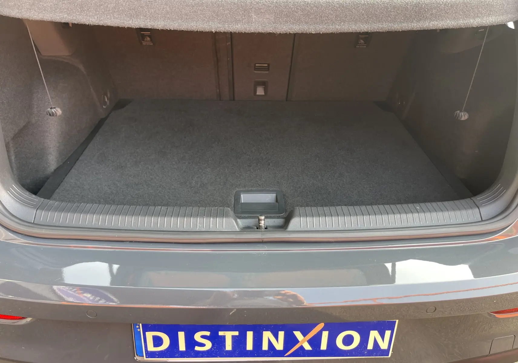 Coffre ouvert d'une Volkswagen Golf VIII GTI gris, vue arrière mettant en valeur l'espace de chargement vide.