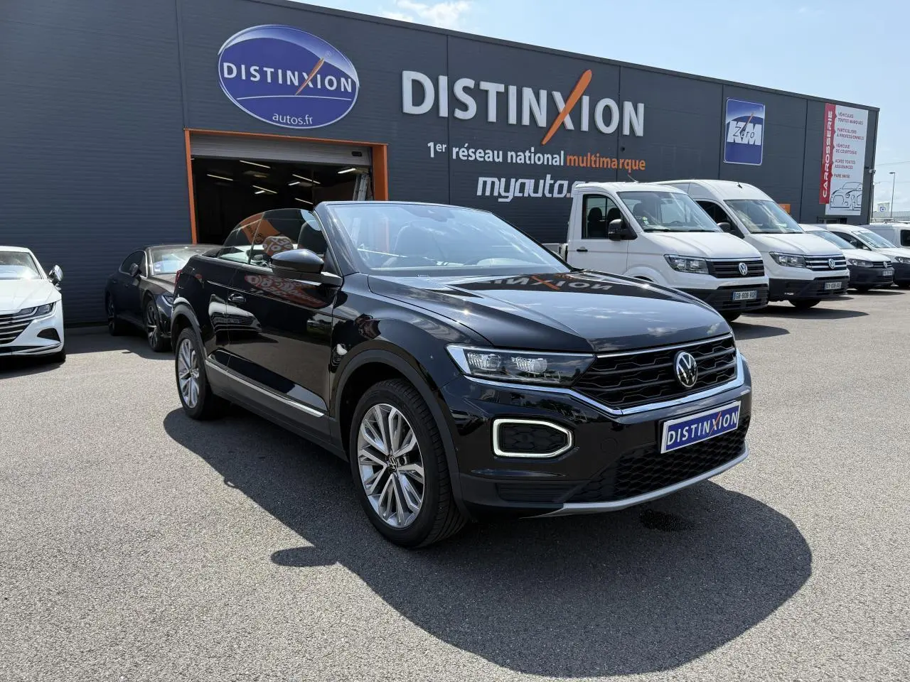 Volkswagen T-Roc Cabriolet noir nacré en 3/4 avant droit, capote ouverte, jantes alliage 18 pouces visibles.