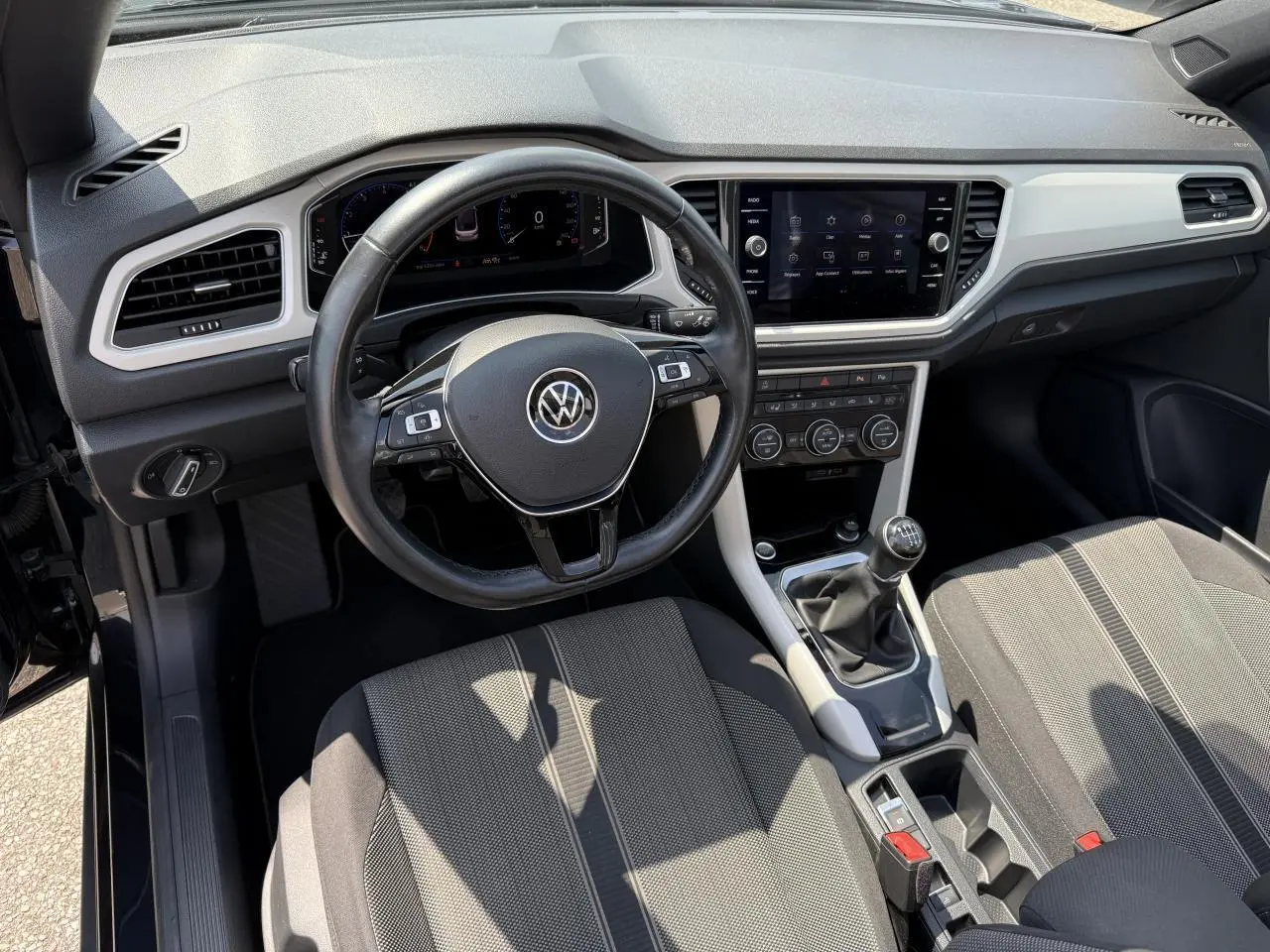 Vue intérieure avant du Volkswagen T-Roc Cabriolet 2021 avec tableau de bord numérique et volant cuir multifonction.