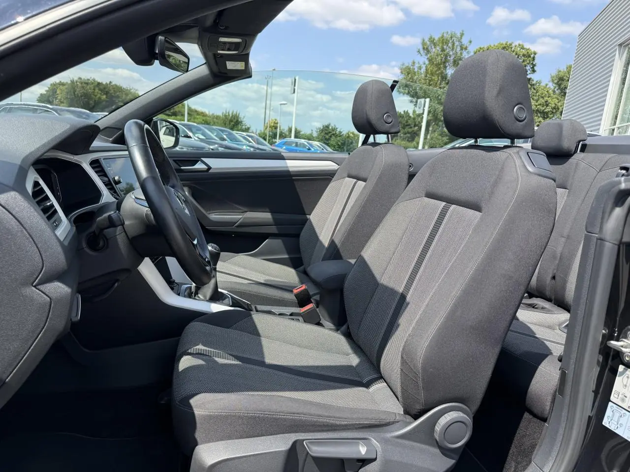 Vue intérieure côté conducteur du Volkswagen T-Roc Cabriolet 2021 avec sièges tissu noirs et volant multifonction.
