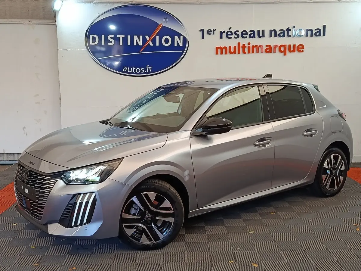 Peugeot 208 gris clair vue 3/4 avant droit, phares LED allumés et jantes alliage distinctives.