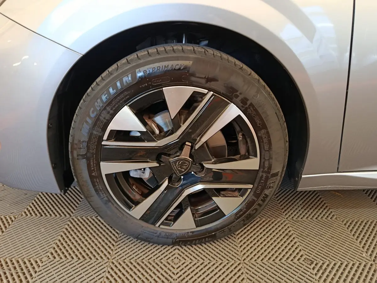 Gros plan sur la roue avant droite gris clair de la Peugeot 208 PureTech 100 S&S Allure avec jante noire et argentée.