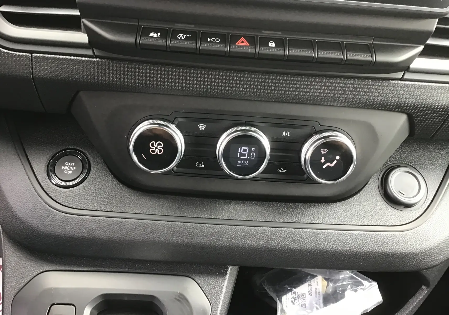 Détail du tableau de bord du Renault Trafic Fourgon gris comète, montrant les commandes de climatisation et le bouton Start/Stop.