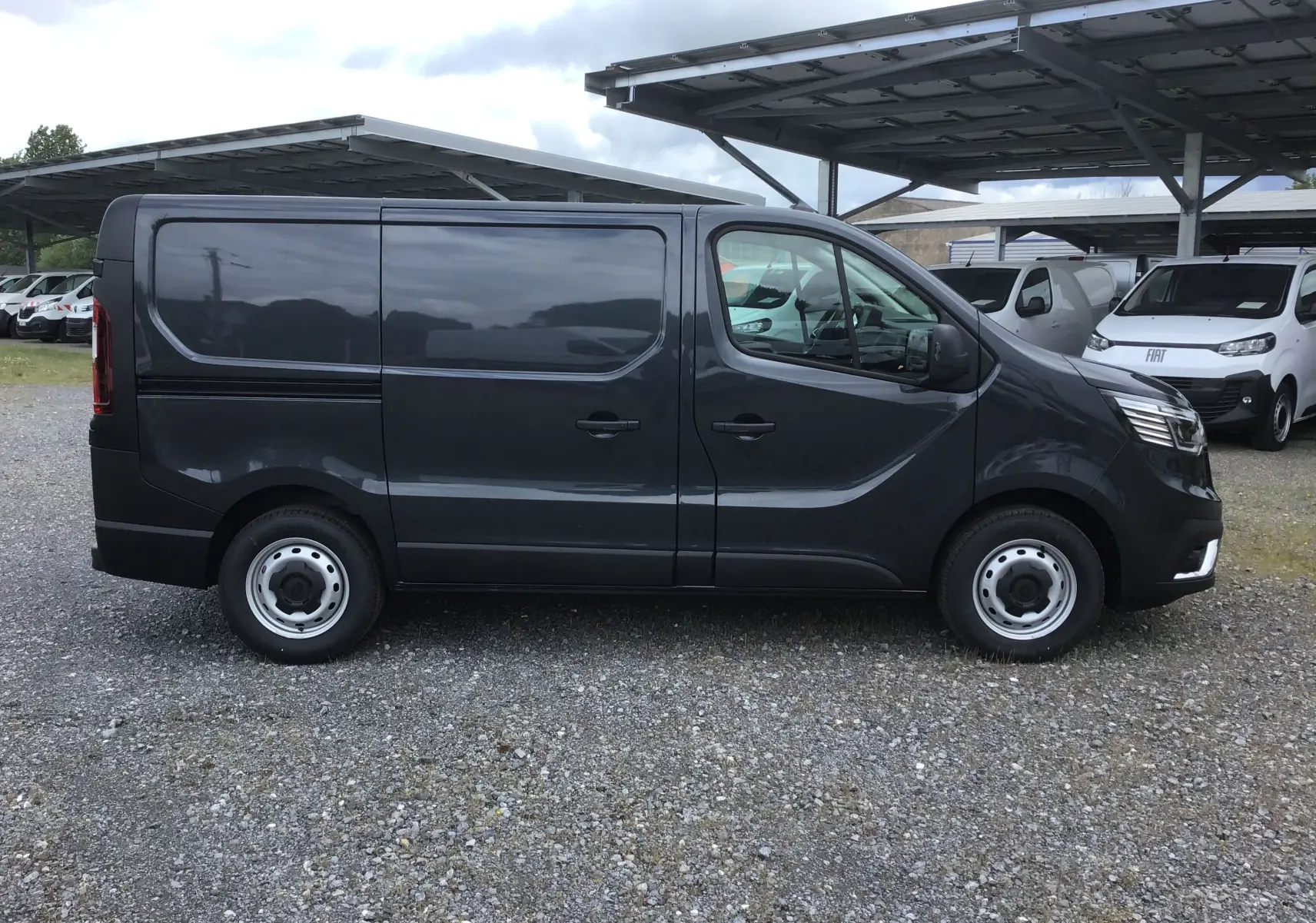 Profil côté droit d’un Renault Trafic Fourgon gris comète 2025, avec jantes acier et carrosserie lisse sans vitres arrière.