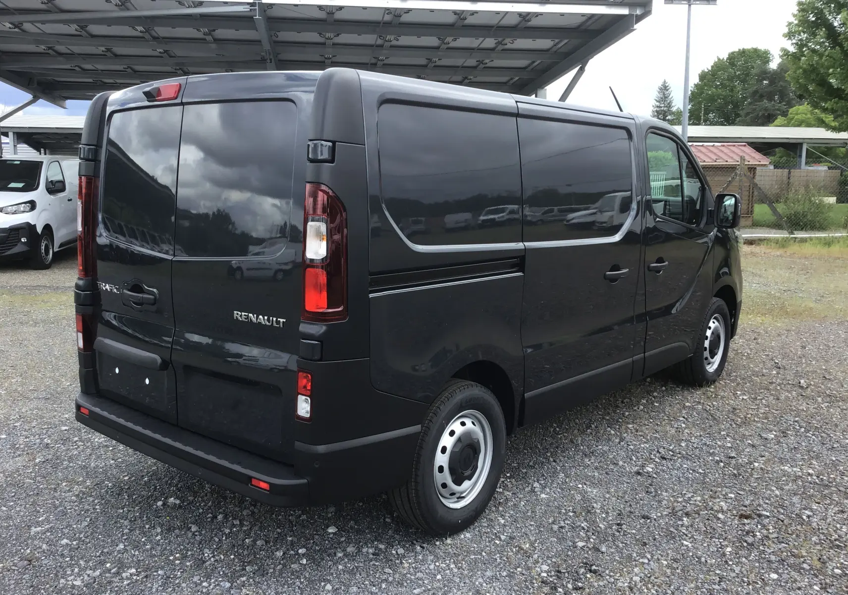 Vue 3/4 arrière droite d’un Renault Trafic Fourgon gris comète 2025, avec portes arrière fermées et jantes acier.