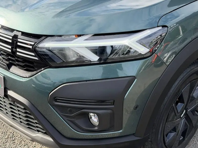 Gros plan sur l'avant droit du Dacia Jogger 2025 en Vert Cèdre métallisé, mettant en valeur le phare LED et la calandre noire.