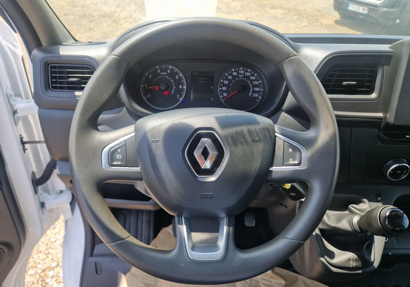 Vue intérieure centrée sur le volant noir Renault d'un Master Châssis Cabine blanc avec levier de vitesse manuel visible.