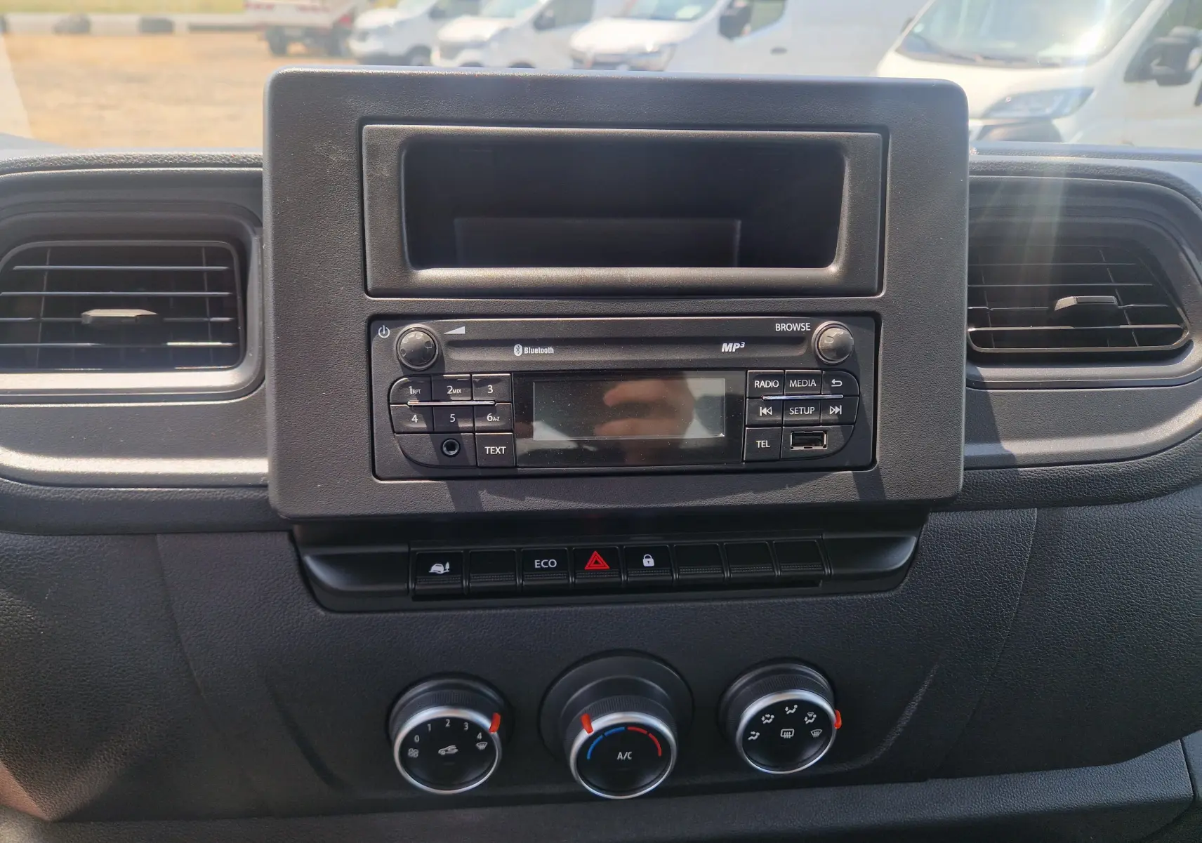 Tableau de bord noir du Renault Master Châssis Cabine 2024, vue frontale centrée sur la radio et les commandes de climatisation.