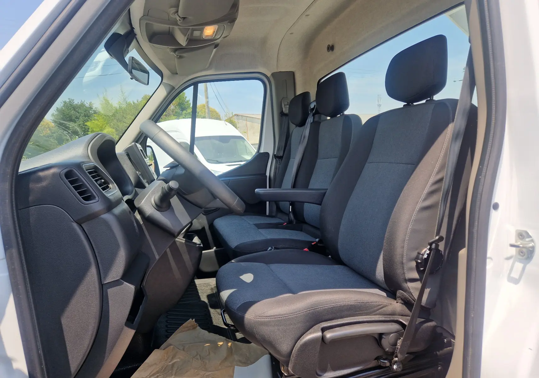 Vue intérieure côté conducteur du Renault Master Châssis Cabine blanc 2024, montrant les sièges gris et le tableau de bord.