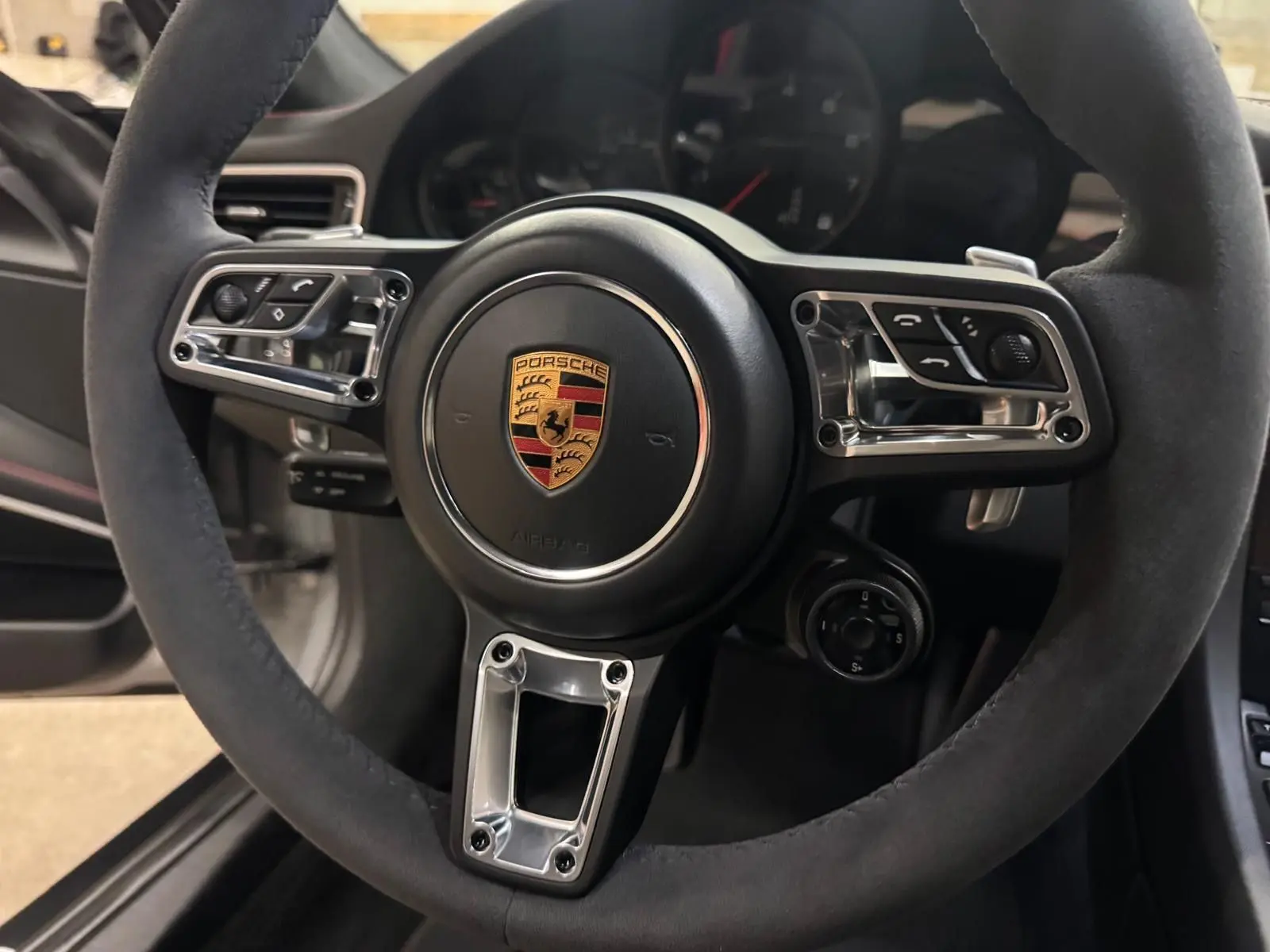 Gros plan sur le volant GT+ en alcantara noir de la Porsche 911 991 2 Carrera T Gris GT Silver, intérieur noir bordeaux.