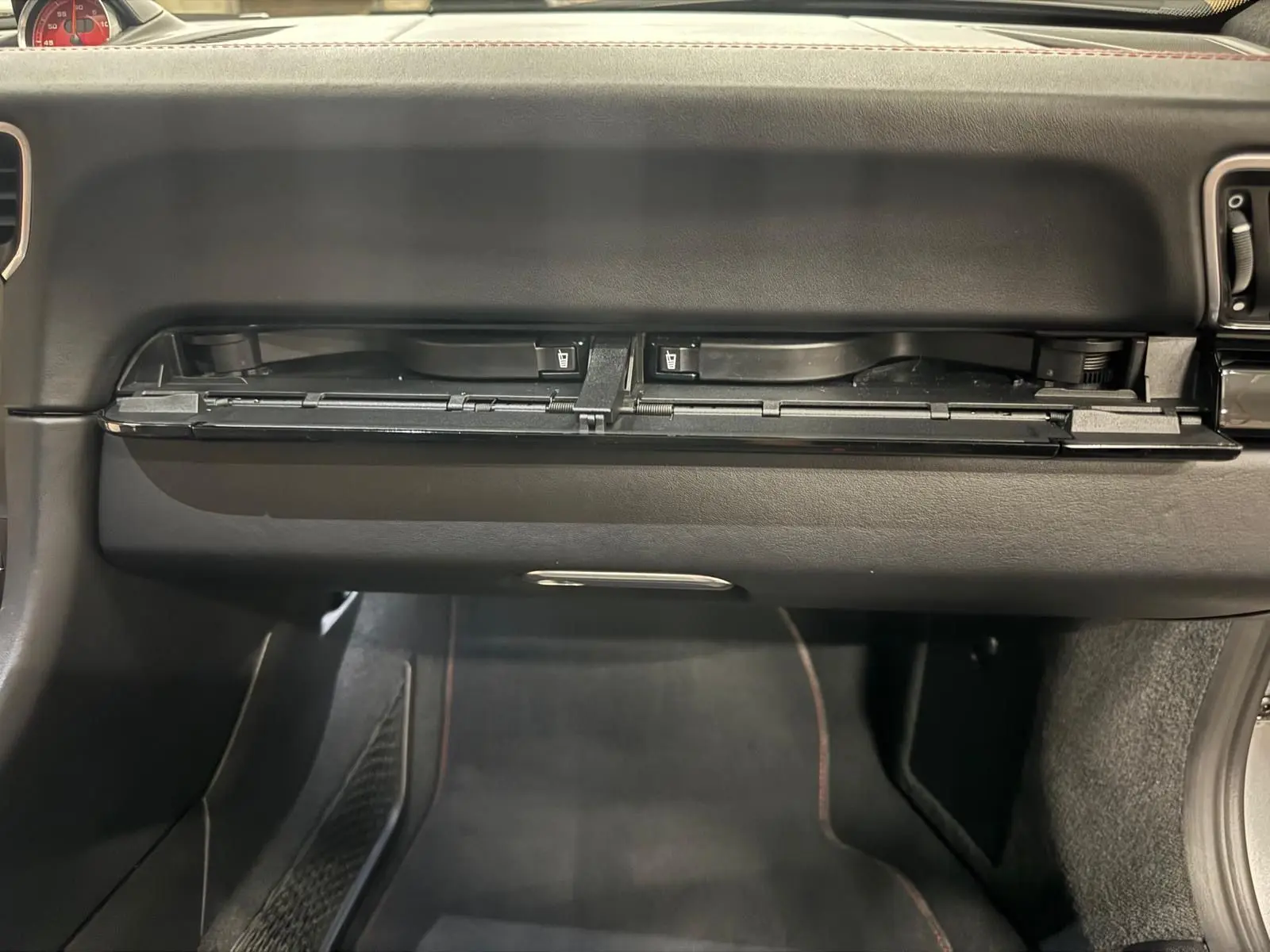 Vue intérieure du coffre à gants ouvert sur une Porsche 911 991 2 Carrera T gris GT Silver, montrant le tableau de bord noir.
