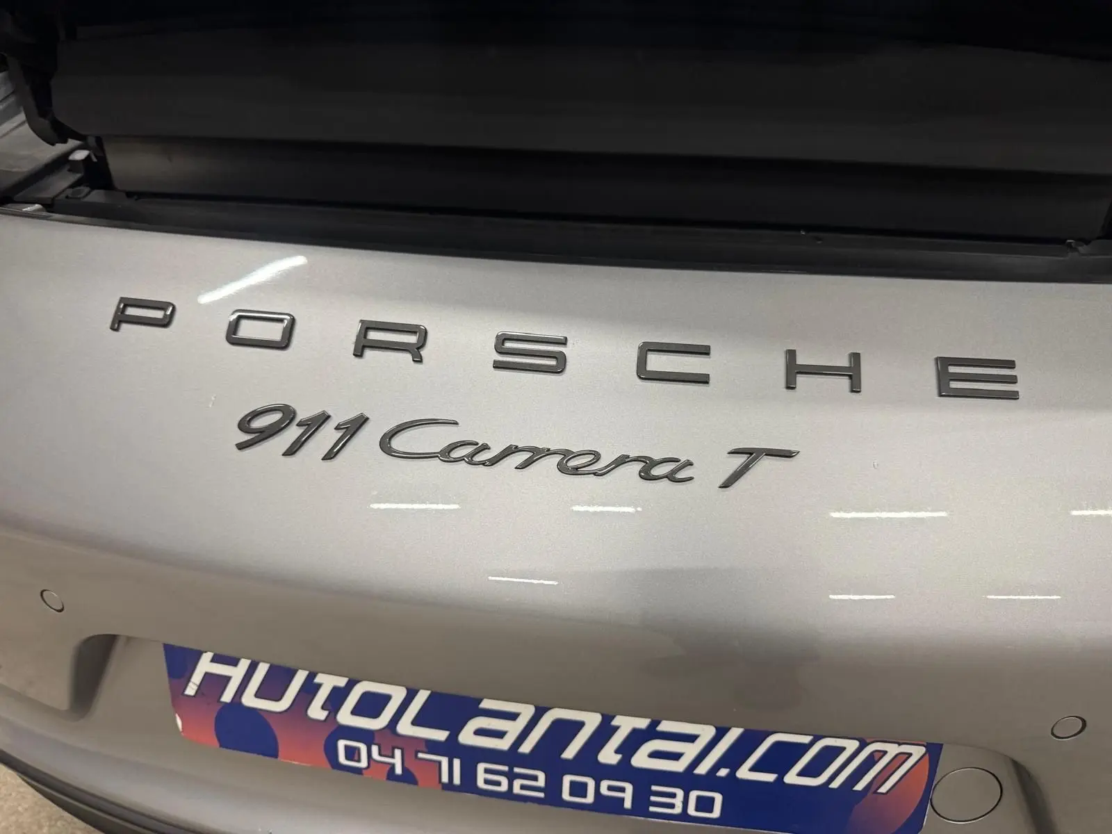 Gros plan sur l'arrière gris GT Silver d'une Porsche 911 Carrera T avec logo et badge distinctifs visibles.