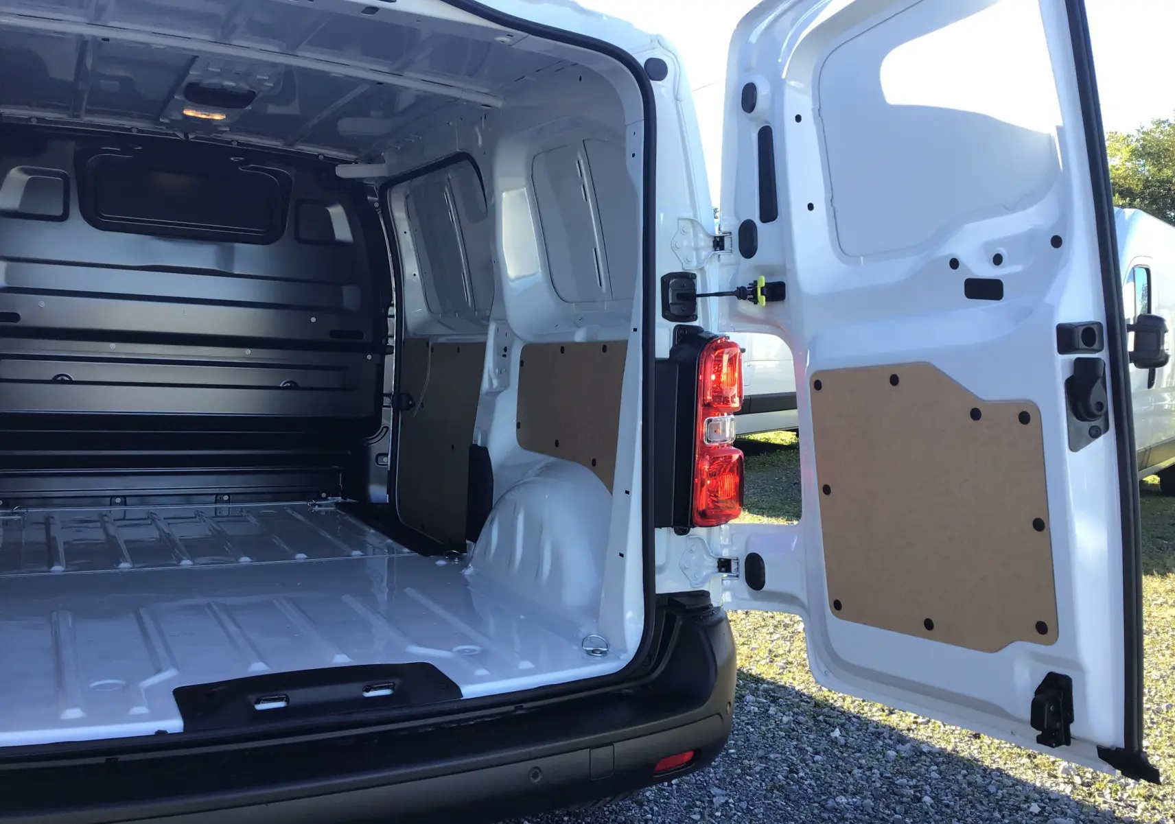 Vue arrière ouverte du fourgon blanc Peugeot Expert 2024 montrant l'intérieur vide et les portes arrière battantes.