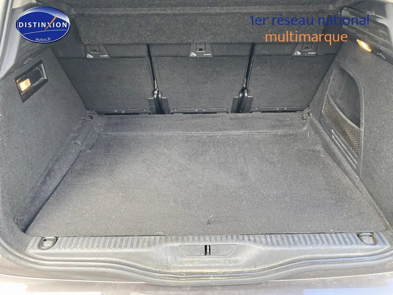 Coffre ouvert du Citroën C4 Picasso gris 2016, montrant un espace de chargement propre et tapis noir.