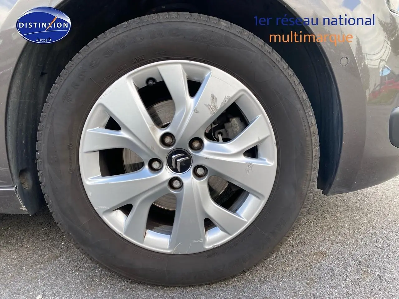 Gros plan sur la roue avant droite grise d'une Citroën C4 Picasso BlueHDi 120 intensive de 2016.