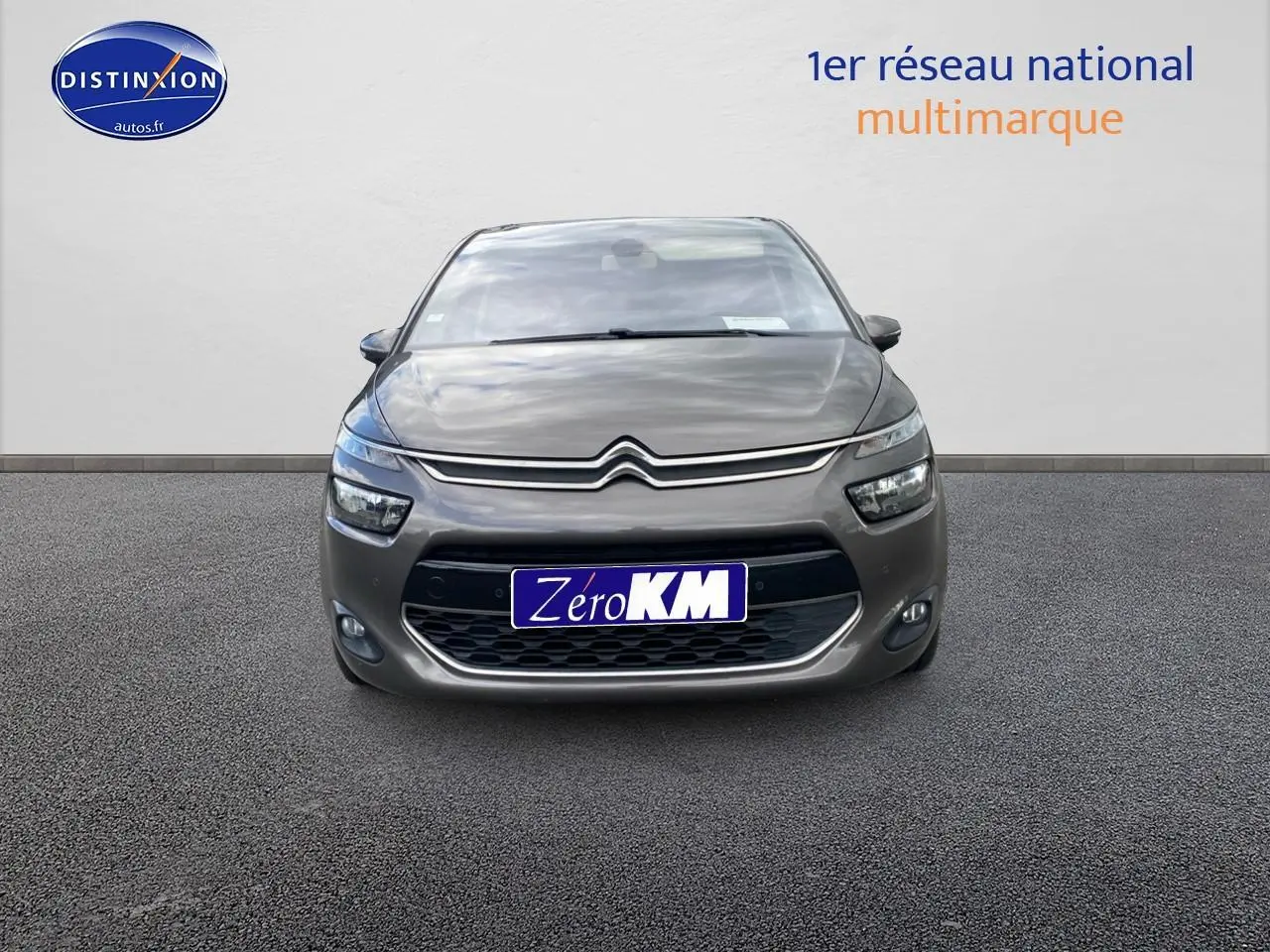 Vue frontale d'une Citroën C4 Picasso gris métallisé avec phares et calandre caractéristiques visibles.