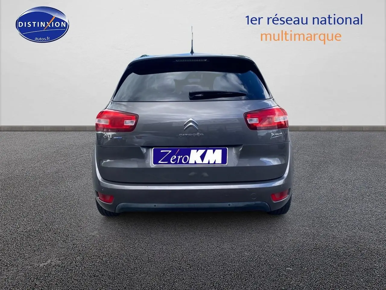 Vue arrière d'une Citroën C4 Picasso gris métallisé avec feux rouges et plaque Zéro KM visible.