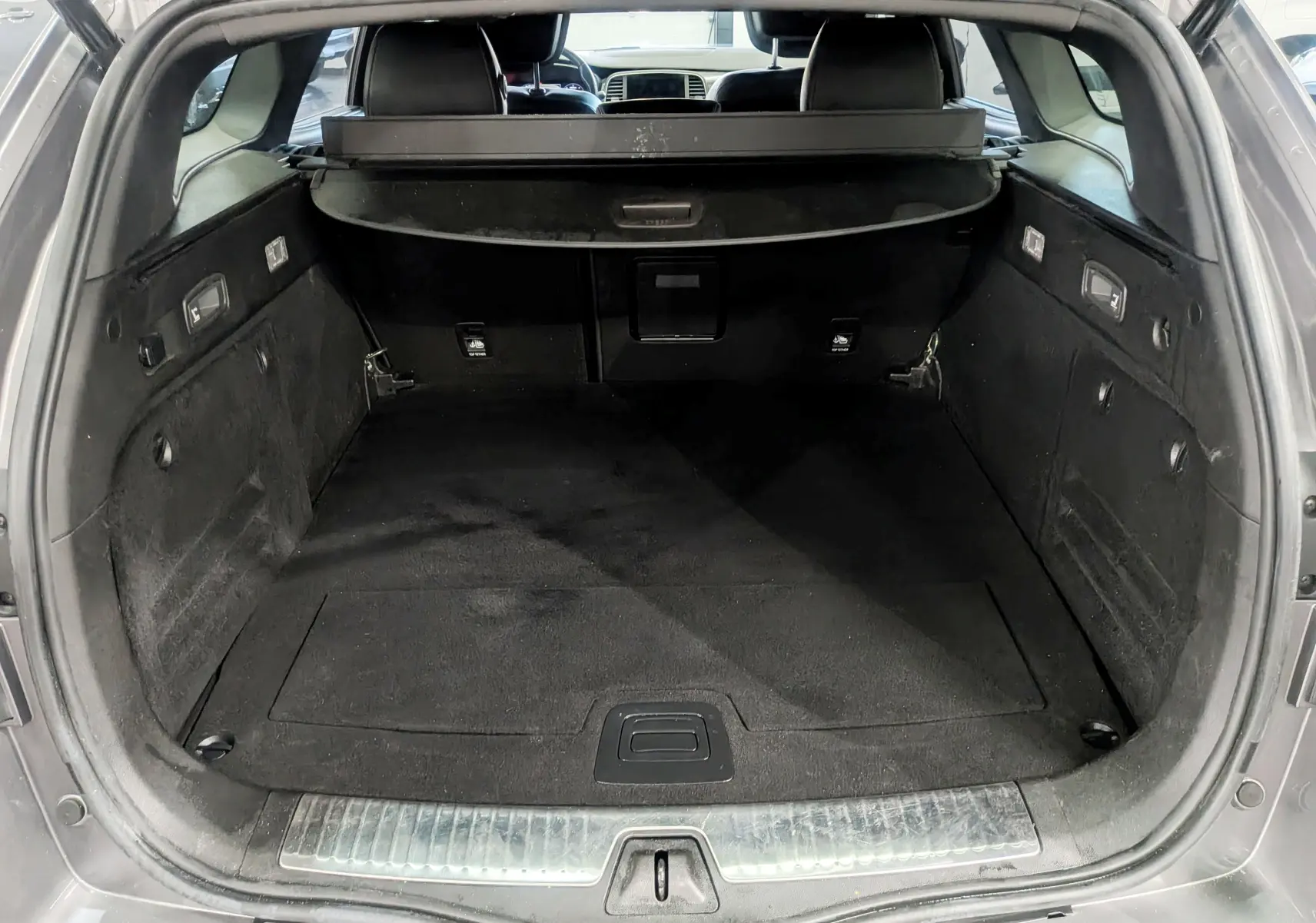 Coffre ouvert d'une Renault Talisman Estate gris Cassiopé, montrant l'espace de chargement intérieur noir et la plage arrière.