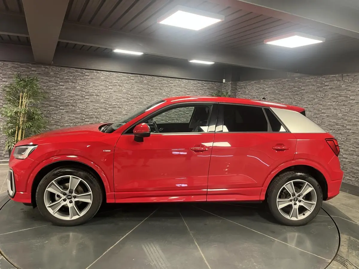 Audi Q2 S line rouge vue de profil côté gauche, toit et montant arrière blancs contrastants, jantes sport 5 branches.
