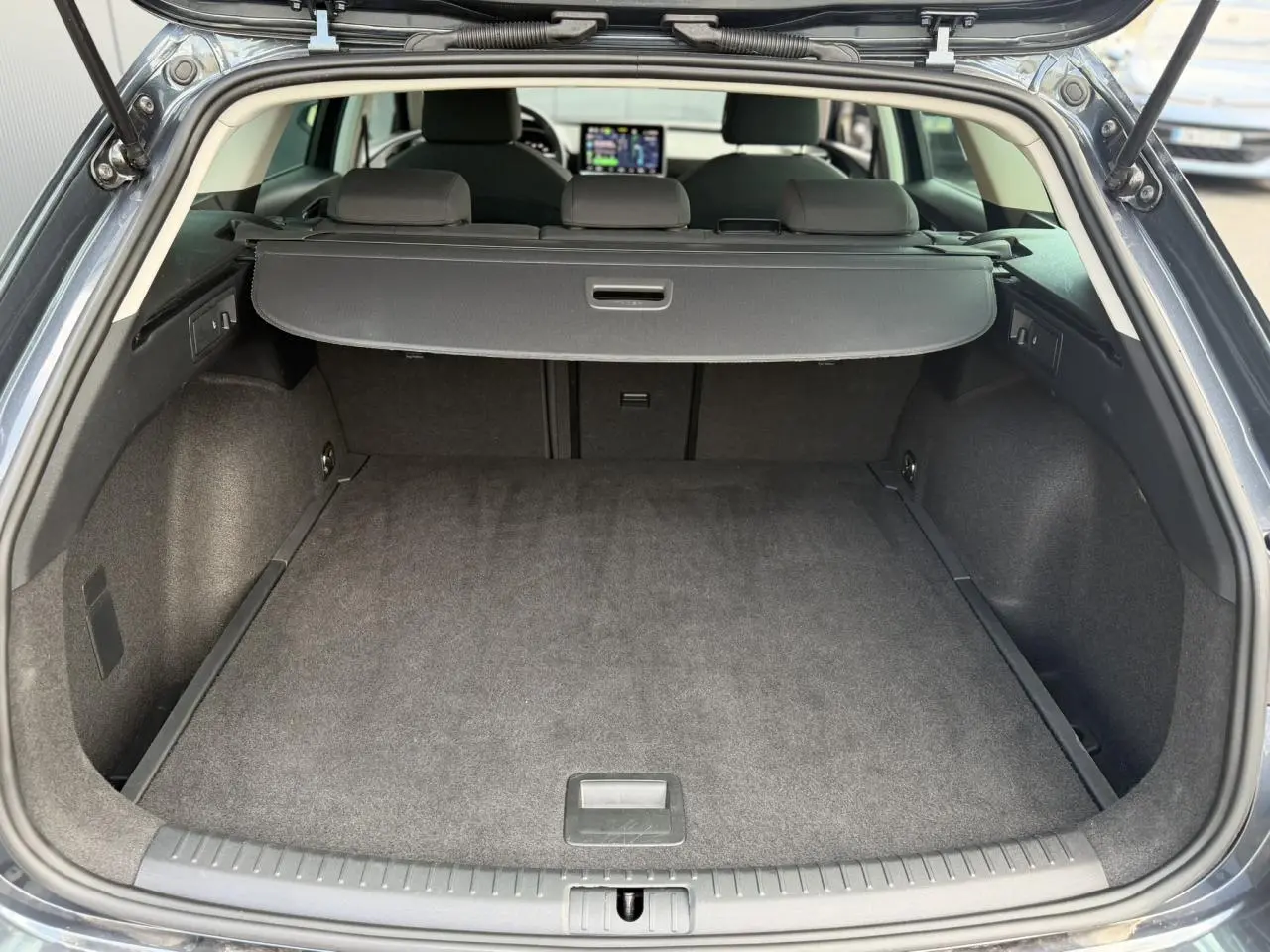 Coffre ouvert vu de l'arrière d'une SEAT LEON ST gris magnétique, avec cache-bagages et intérieur noir.