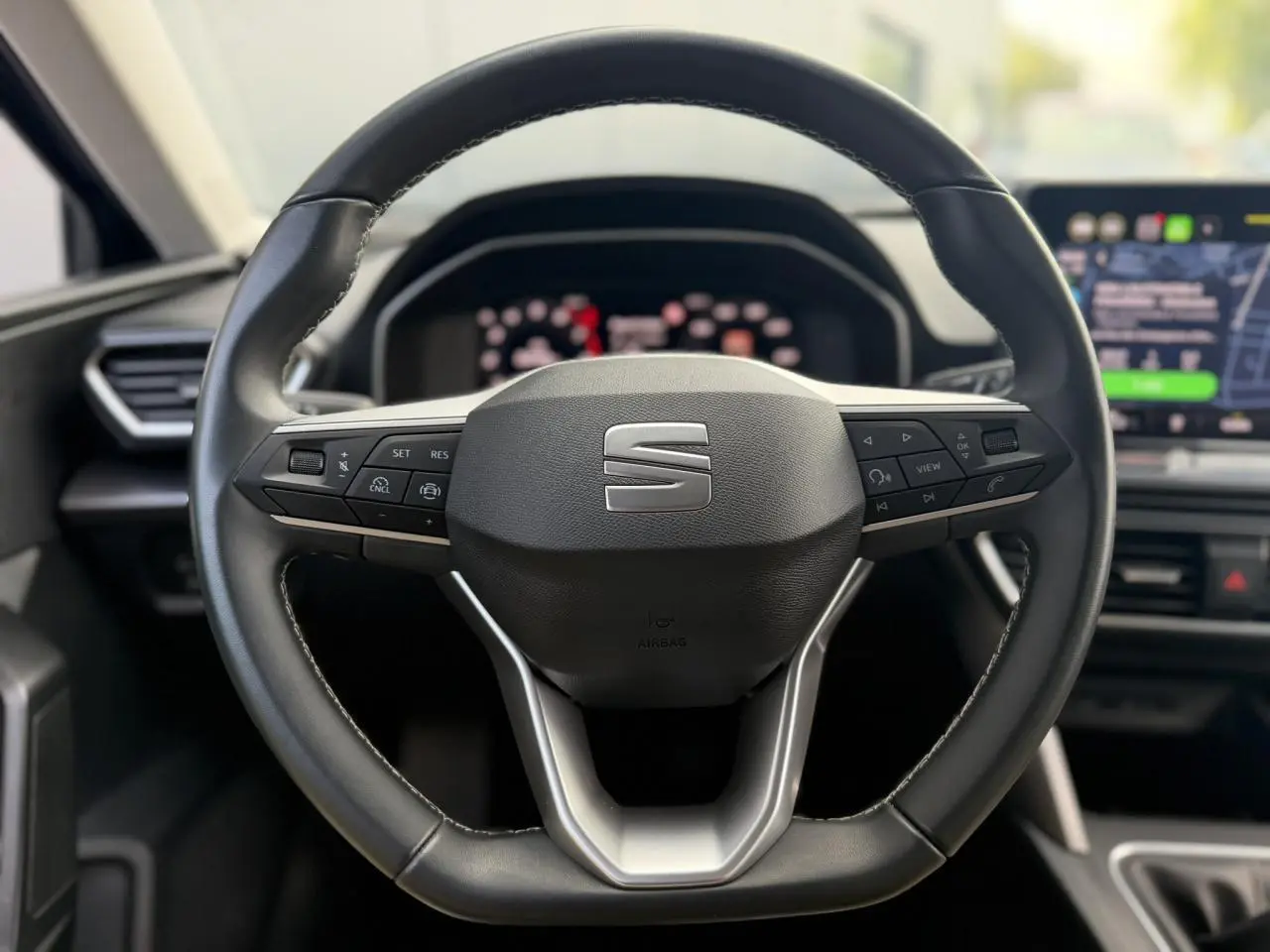 Volant cuir multifonction noir de la SEAT LEON ST 2025, vue frontale centrée sur les commandes intégrées.