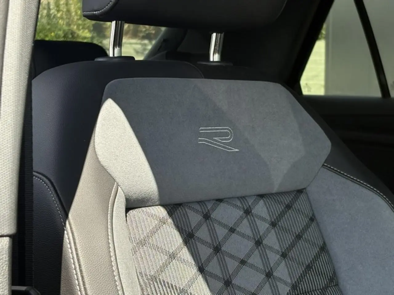 Gros plan sur le siège avant en cuir et alcantara gris avec logo R-Line brodé, intérieur du Volkswagen T-Roc 2025.