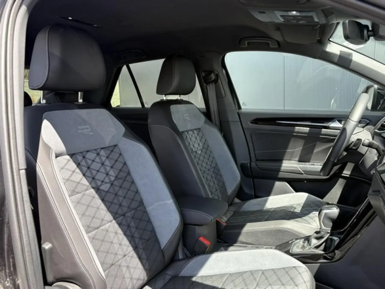 Vue intérieure côté conducteur du Volkswagen T-Roc 1.5 TSI R-Line 2025, sièges cuir et alcantara gris avec surpiqûres R-Line.