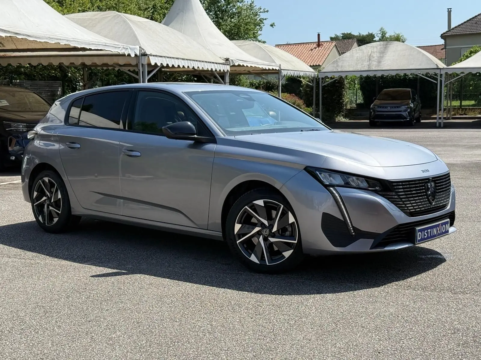 Peugeot 308 gris Artense vue 3/4 avant droit, avec jantes alliage et calandre noire distinctive.
