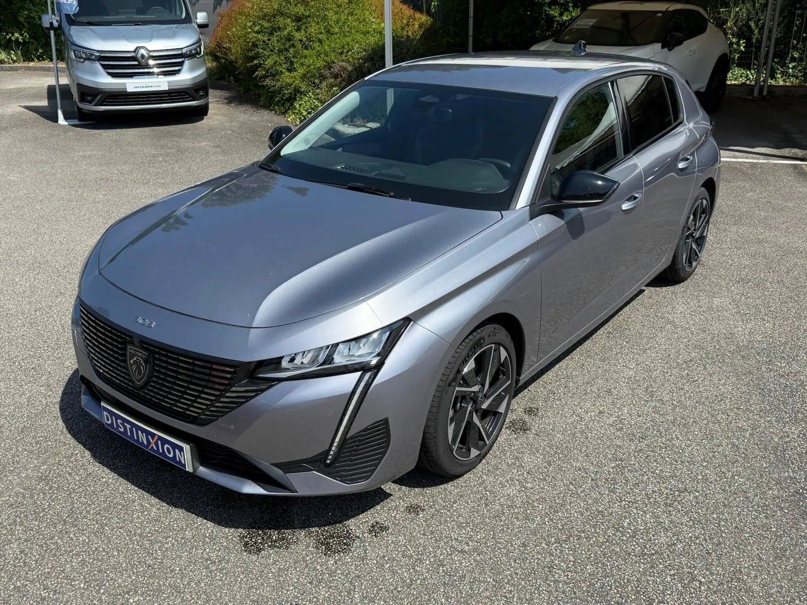 Peugeot 308 gris Artense vue 3/4 avant droit, mettant en valeur ses phares LED et sa calandre noire distinctive.