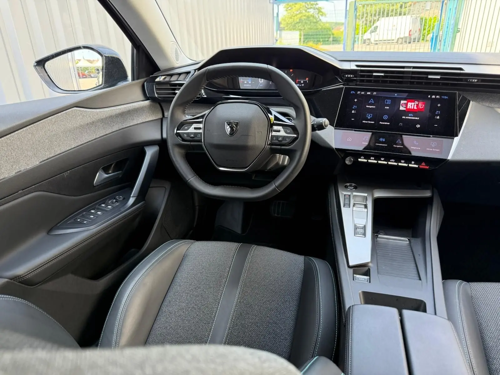 Vue intérieure avant de la Peugeot 308 2024, tableau de bord moderne avec écran tactile et volant compact noir.