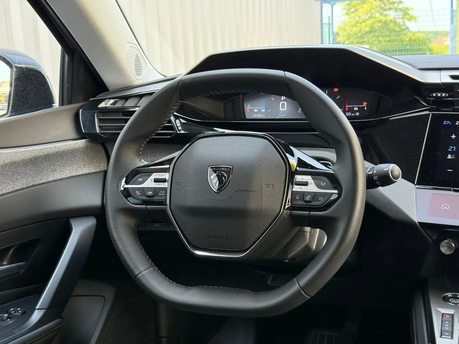 Vue rapprochée du volant cuir noir de la Peugeot 308 2024 avec tableau de bord digital et commandes intégrées.