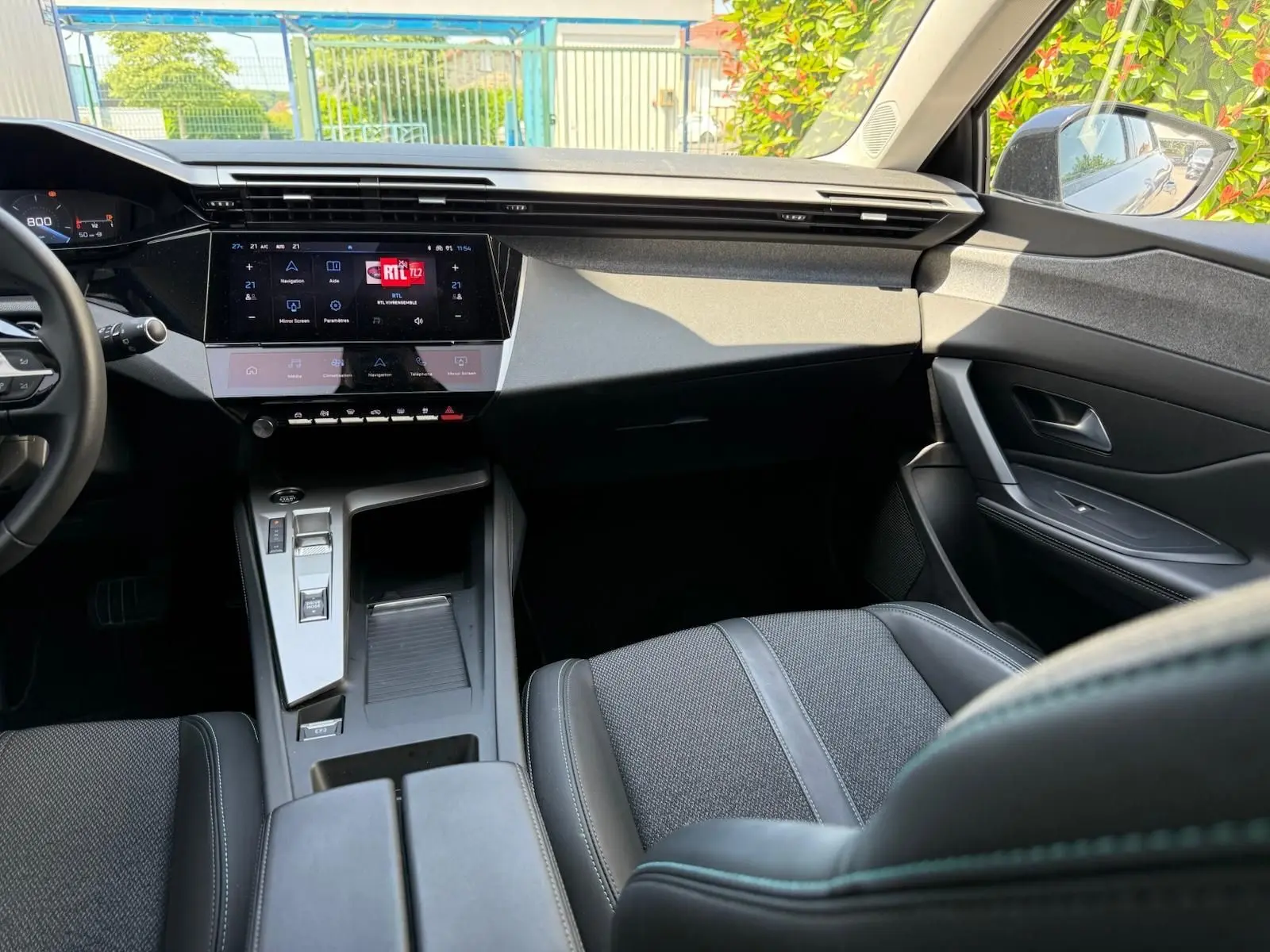 Intérieur avant droit de la Peugeot 308 2024 gris Artense, avec tableau de bord numérique et console centrale moderne.