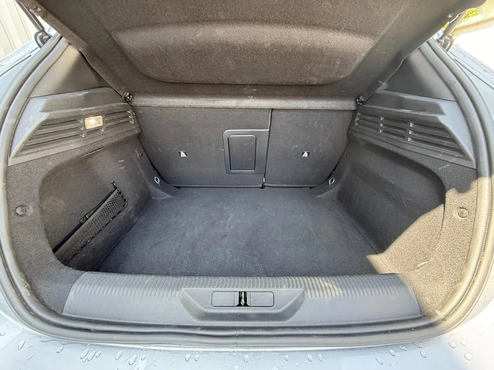 Coffre ouvert d'une Peugeot 308 gris Artense, montrant un espace de chargement propre et bien agencé.