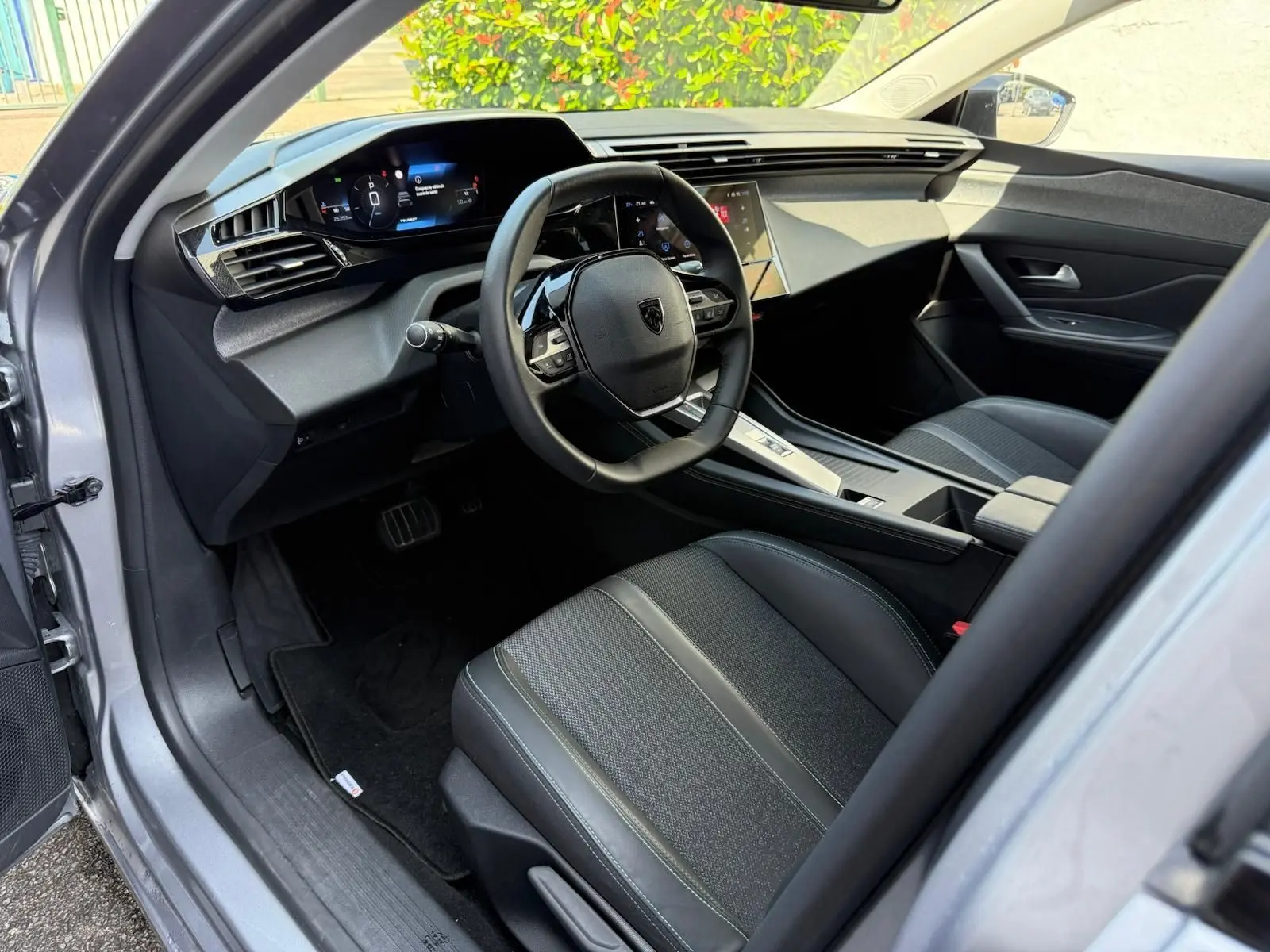 Intérieur avant droit de la Peugeot 308 gris Artense 2024, tableau de bord numérique et volant compact multifonction.